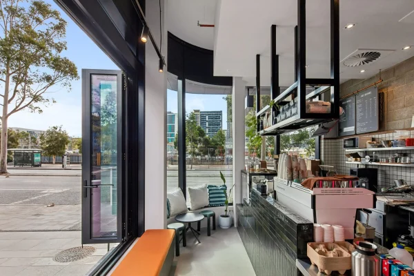 View through the open bi-fold glazed shopfront of Finns Espresso, looking out to Wellington Street, with the tiled counter and menu boards visible inside.